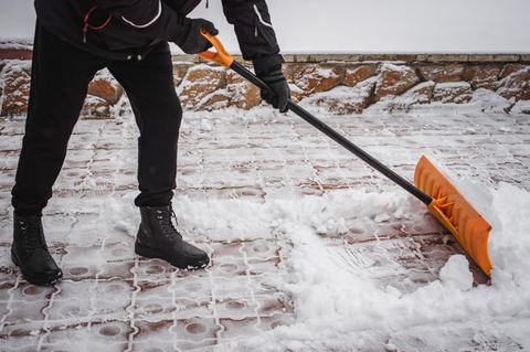 Schneeschieber Nach einem Schneefall entfernt eine Person Schnee vor dem Haus