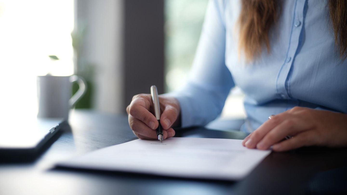 Eine Frau unterschreibt ein Dokument