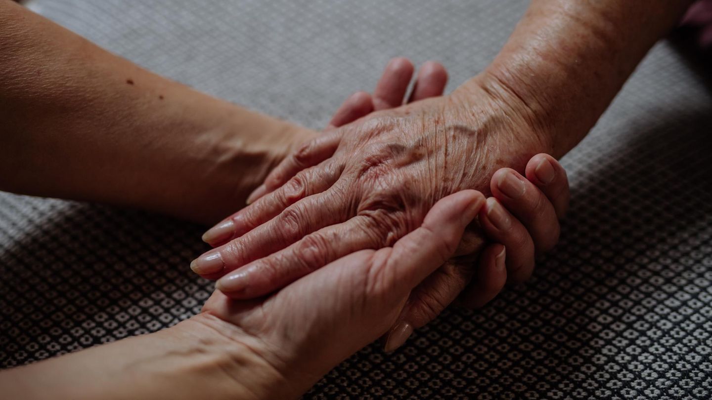 Trauer: Hände halten sich im halb-Schatten Trauer: Hände halten sich im halb-Schatten