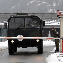 Ein Militärfahrzeug passiert einen Checkpunkt. Zwei Soldaten sprechen miteinander