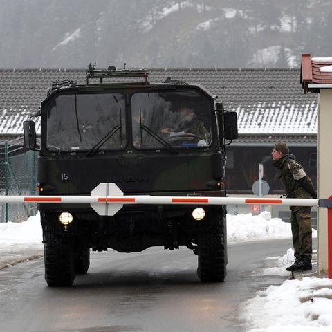 Ein Militärfahrzeug passiert einen Checkpunkt. Zwei Soldaten sprechen miteinander