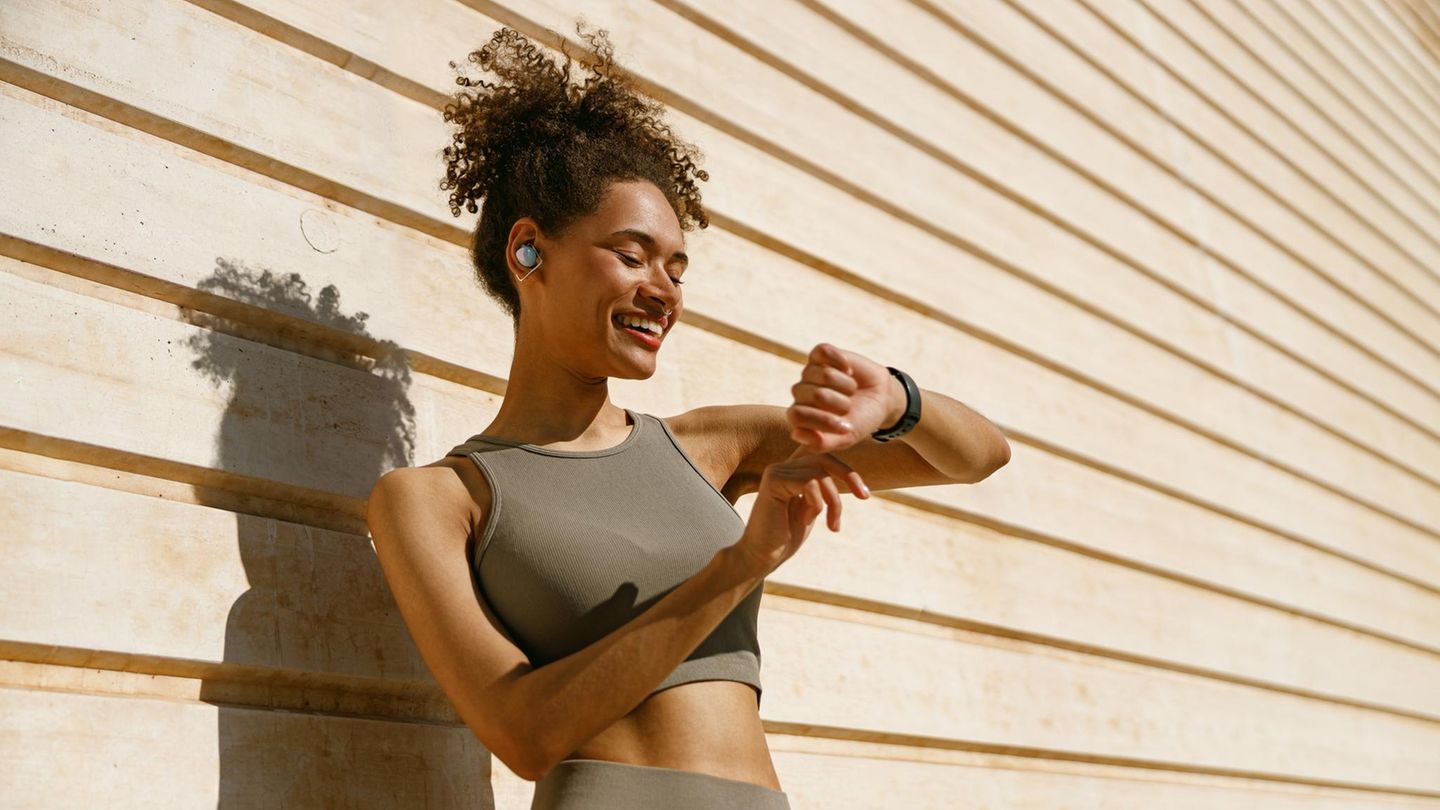 Frau schaut auf ihre Fitness-Smartwatch und misst Schritte Frau schaut auf ihre Fitness-Smartwatch und misst Schritte