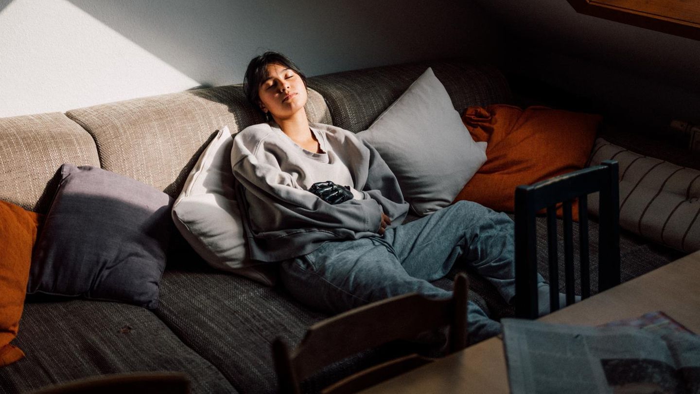 Eine junge Frau der Gen Z ruht sich auf einer Couch aus Eine junge Frau der Gen Z ruht sich auf einer Couch aus