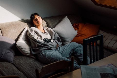 Eine junge Frau der Gen Z ruht sich auf einer Couch aus Eine junge Frau der Gen Z ruht sich auf einer Couch aus