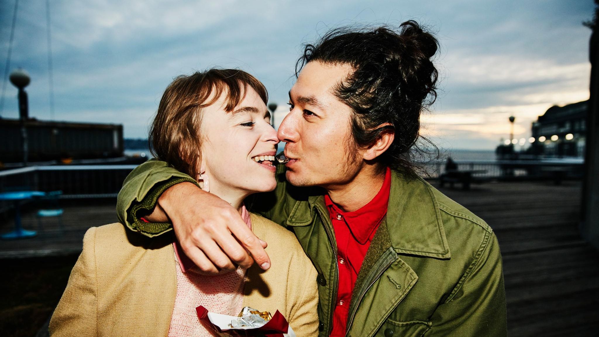 Gefühle: Ein Paar teilt sich Schokolade. Er umarmt sie dabei. Gefühle: Ein Paar teilt sich Schokolade. Er umarmt sie dabei.