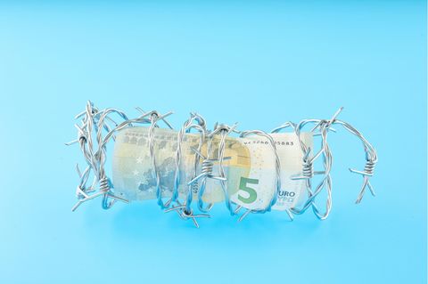 Enterben: Geldschein in Stacheldraht Enterben: Geldschein in Stacheldraht