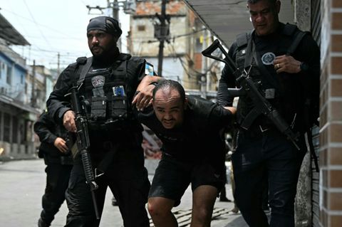 Polizisten mit festgenommenem Verdächtigen in Vila Cruzeiro