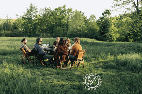Eien Gruppe Menschen sitzt auf einer Wiese in einem Kreis
