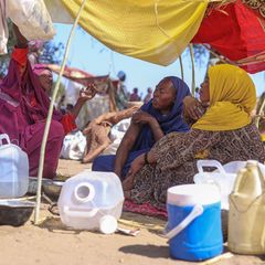 Geflohene Frauen aus al Faschir sitzen in einem Flüchtlingslager im Sudan unter Sonnensegeln