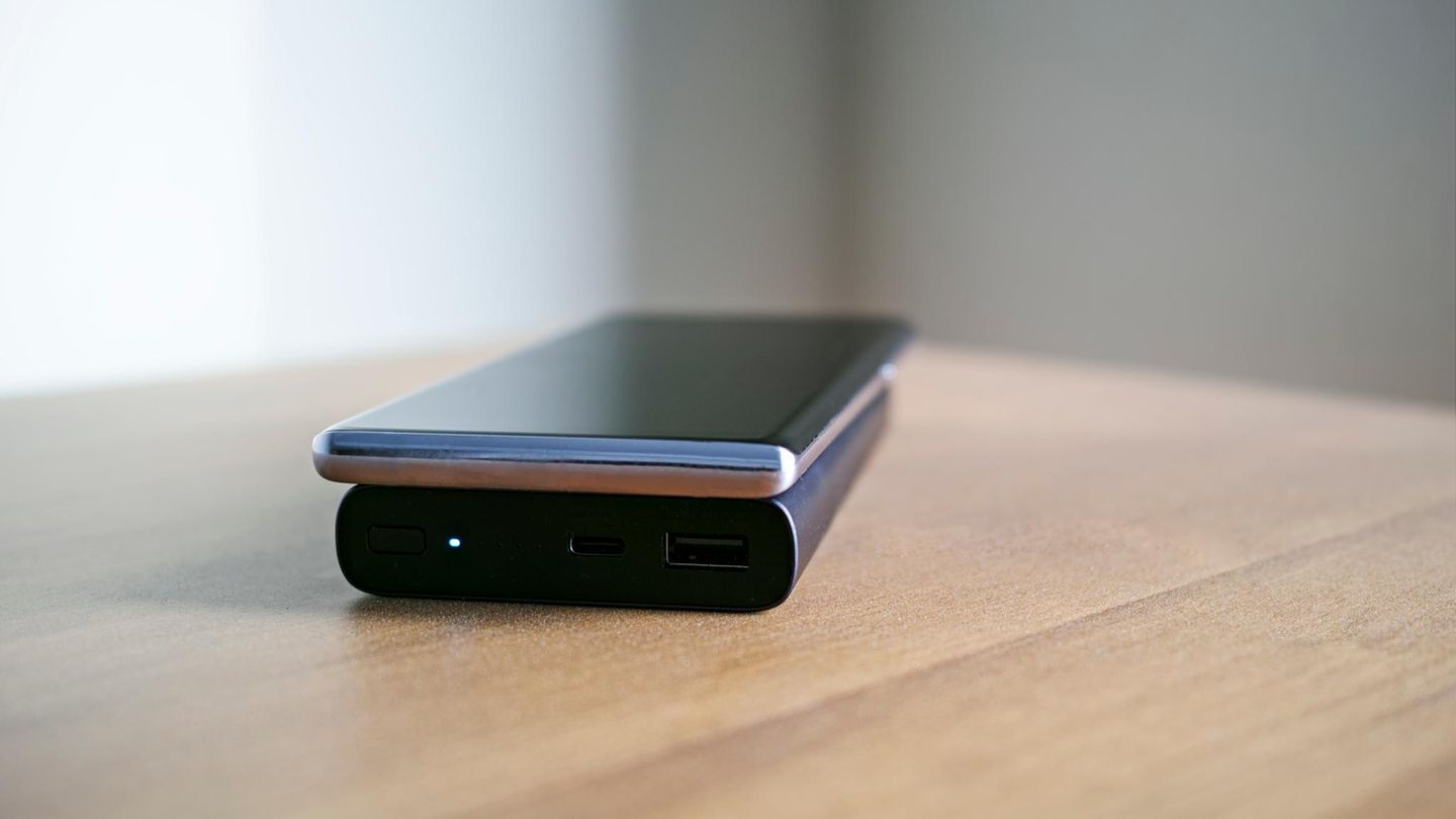 Person lädt Smartphone mit Powerbank auf