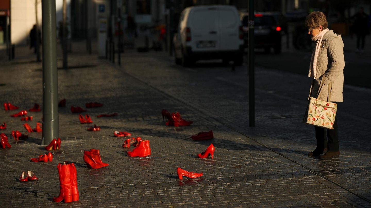 Stadtbild-Debatte (Symbolbild) Stadtbild-Debatte (Symbolbild): Eine Frau schaut sich rot lackierte Schuhe auf der Straße an, ein Mahnmal