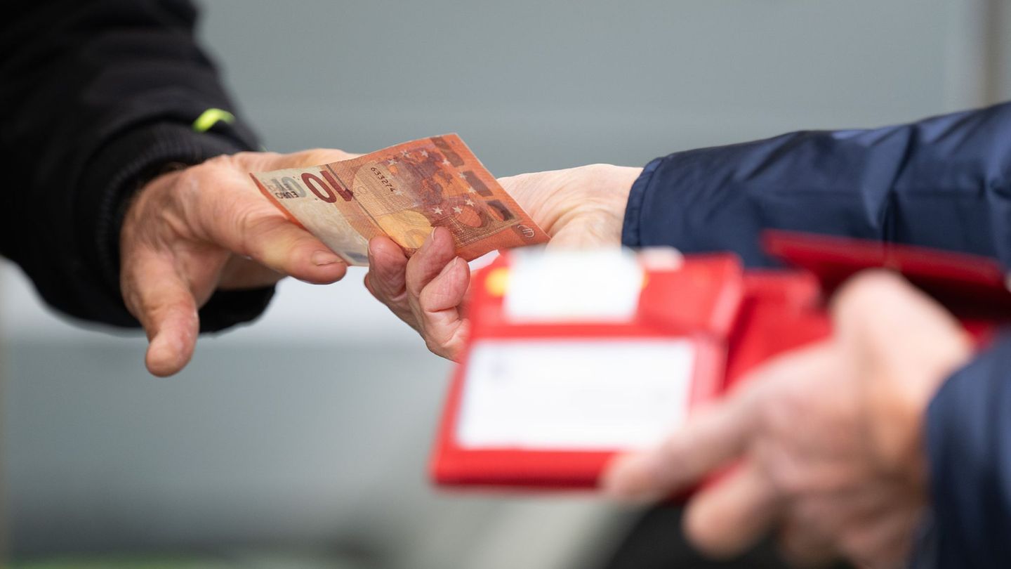 Eine Person überreicht einer anderen einen 10-Euro-Schein: Symbolbild deutsche Wirtschaft Eine Person überreicht einer anderen einen 10-Euro-Schein: Symbolbild deutsche Wirtschaft
