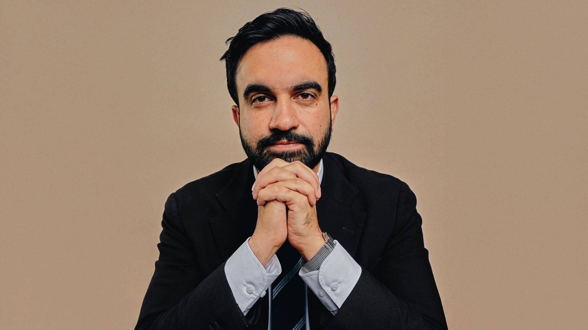 Zohran Momdani im Anzug vor einem neutralen Hintergrund