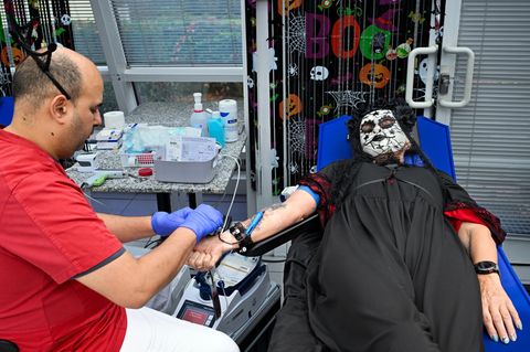 Zwischen Halloween-Deko und im Kostüm spendet eine Frau Blut. Foto: Soeren Stache/dpa
