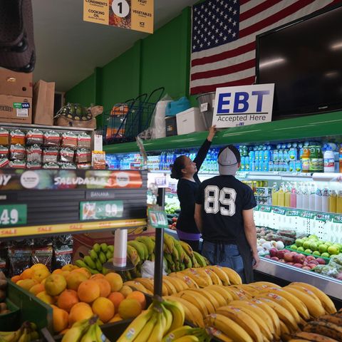 Eine Ladenbesitzerin stellt ein Banner mit der Aufschrift "EBT (Electronic Benefit Transfer) Accepted Here" auf