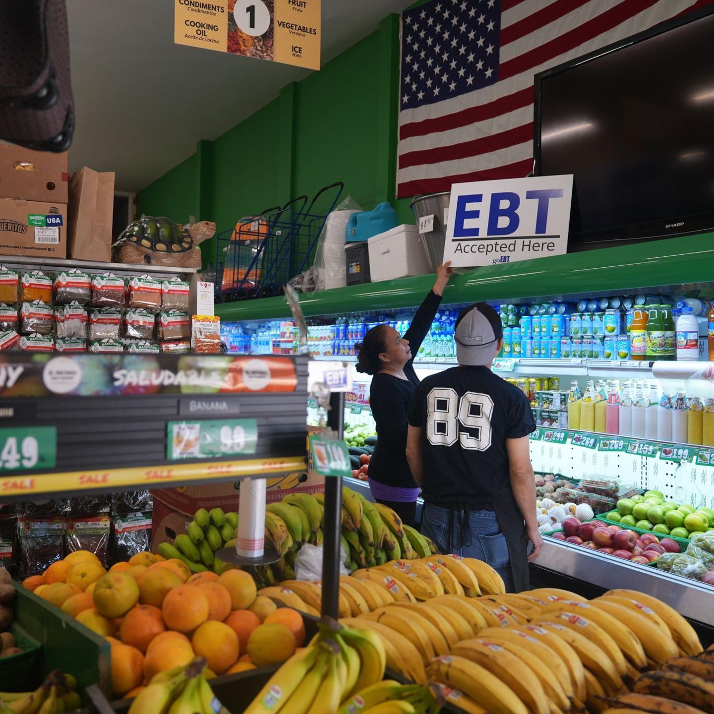 Eine Ladenbesitzerin stellt ein Banner mit der Aufschrift "EBT (Electronic Benefit Transfer) Accepted Here" auf