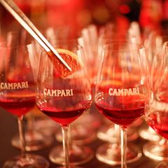 Ein Barkeeper gibt eine Blutorange in Campari-Gläser