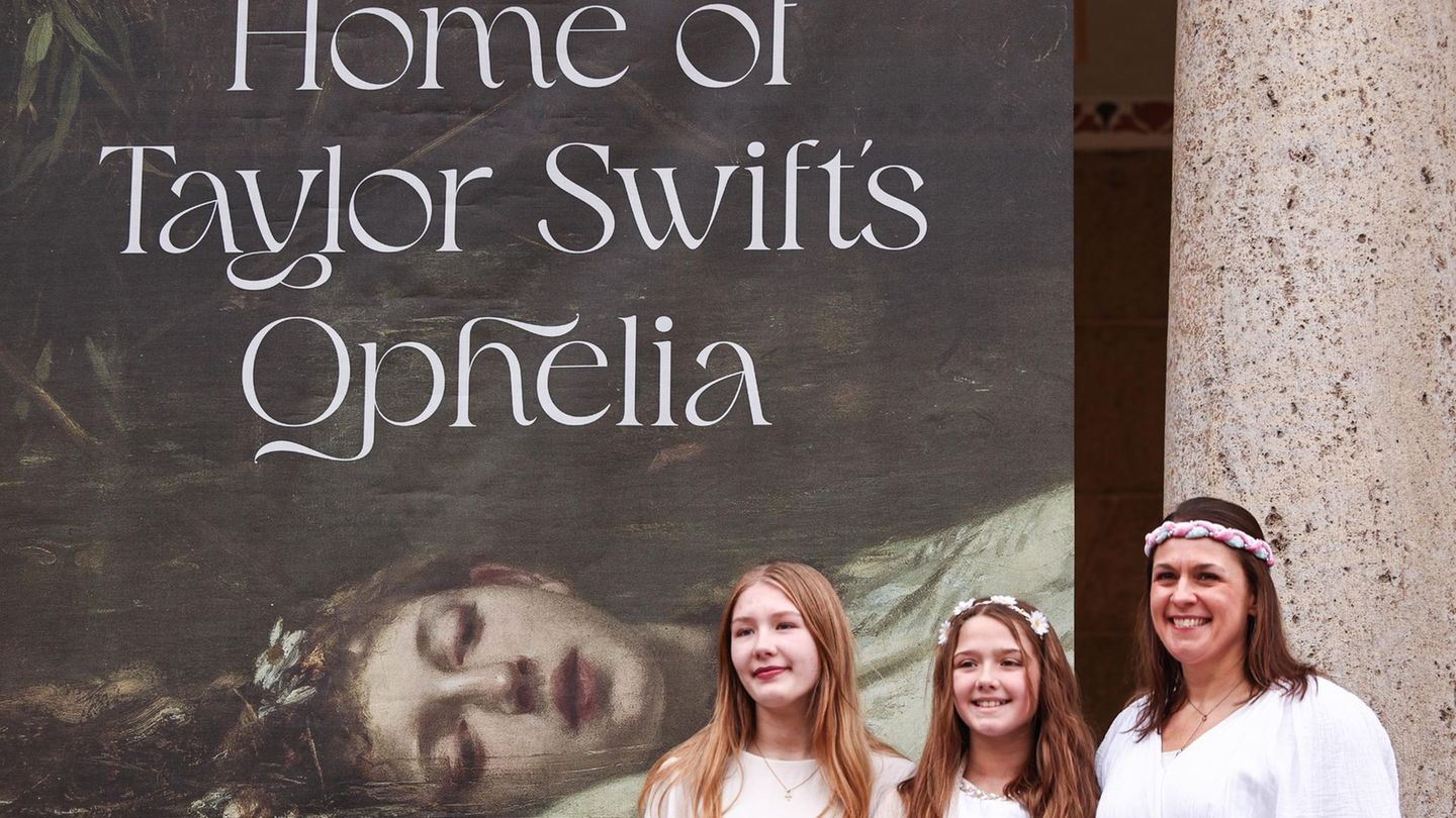 Fans stehen als Ophelia verkleidet vor einem Banner mit der Aufschrift "Home of Taylor Swifts Ophelia"