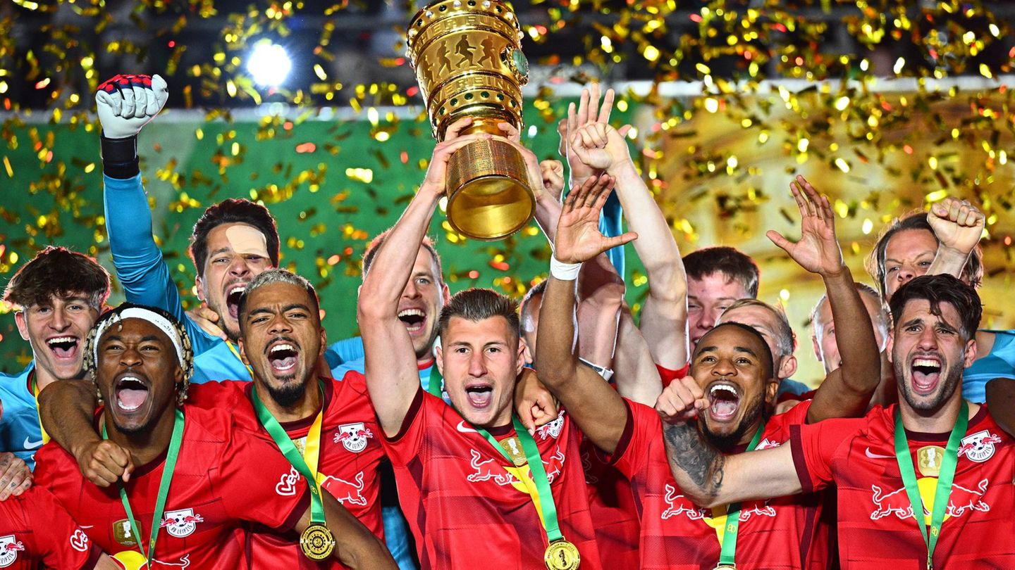 Leipzigs Willi Orban hält die Siegertrophäe in die Höhe und bejubelt mit seinen Teamgefährten den zweiten Pokalsieg in der Verei