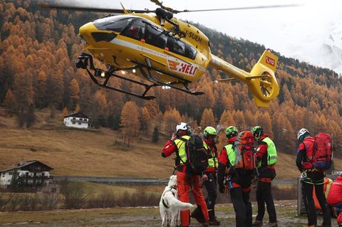 Ein Trupp der Bergwacht steht in Südtirol, während ein gelber Hubschrauber landet