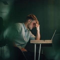 Selbstständiger sitzt vor Laptop in Krisensituation