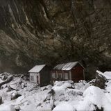 Zwei Hütten unter einer Felsformation im Schnee