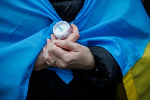 Frau mit ukrainischer Fahne und Kerze
