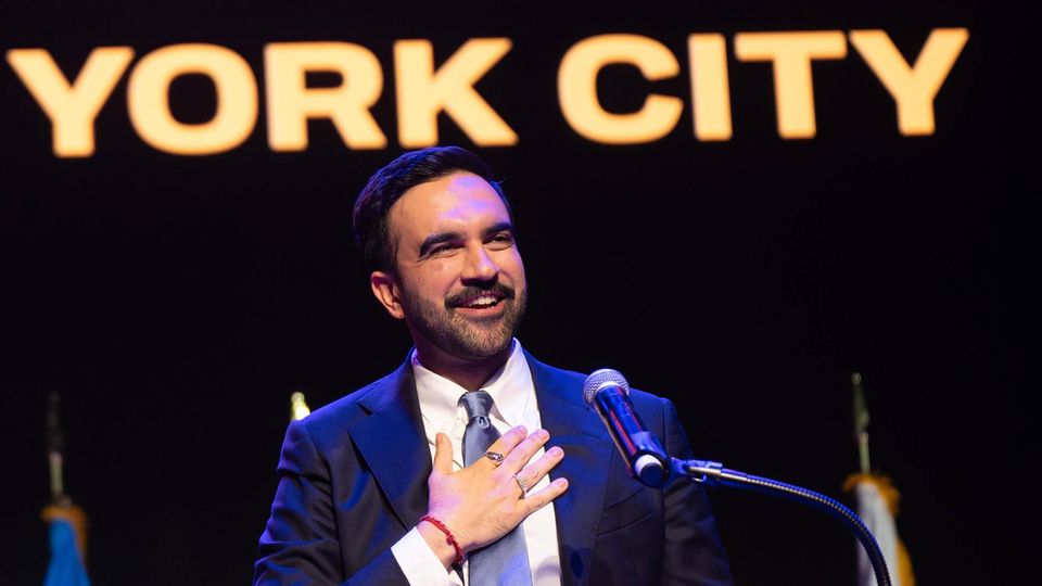 Zohran Mandami mit Anhängern seiner Partei und einem Schild "Our Time Is Now"