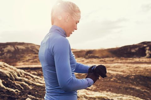 Eine Frau trägt Sporthandschuhe und bedient ihre Smartwatch