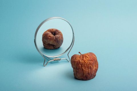 Abnehmspritze, Symbolbild: faltiger geschrumpfter Apfel vor eime Spiegel