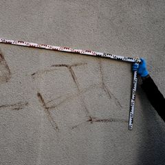 Kriminalexperten messen Hakenkreuze an einem Haus in Hanau