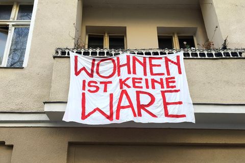 Von einem Balkon hängt ein Transparent mit dem Slogan: "Wohnen ist keine Ware"