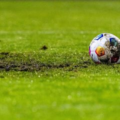 Ein Fußball liegt am Elfmeterpunkt im matschigen Rasen