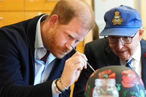 Prinz Harry bemalt in Toronto mit einem Veteranen einen militärischen Helm.