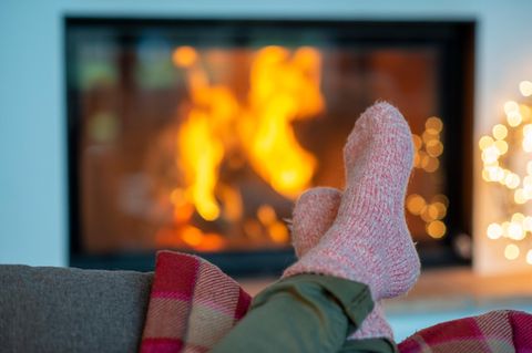 Legs of young woman wearing socks relaxing against fireplace at home