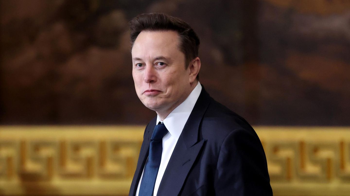Elon Musk in einem Anzug schaut leicht lächelnd an dem Betrachter vorbei