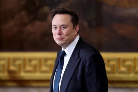 Elon Musk in einem Anzug schaut leicht lächelnd an dem Betrachter vorbei
