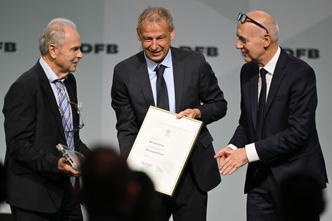 Bernard Dietz (l) wird von Jürgen Klinsmann und DFB-Präsident Bernd Neuendorf für die Ernennung zum Ehrenspielführer gratuliert.