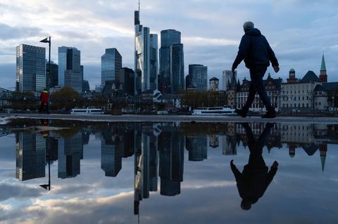 Eine Frau läuft vor der Frankfurter Skyline am Main entlang