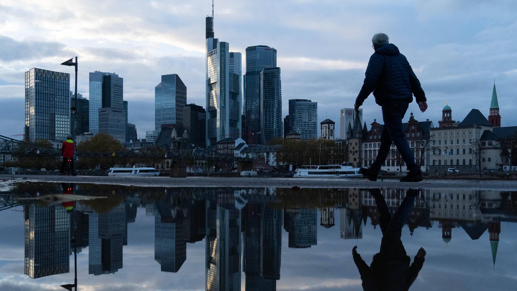 Eine Frau läuft vor der Frankfurter Skyline am Main entlang