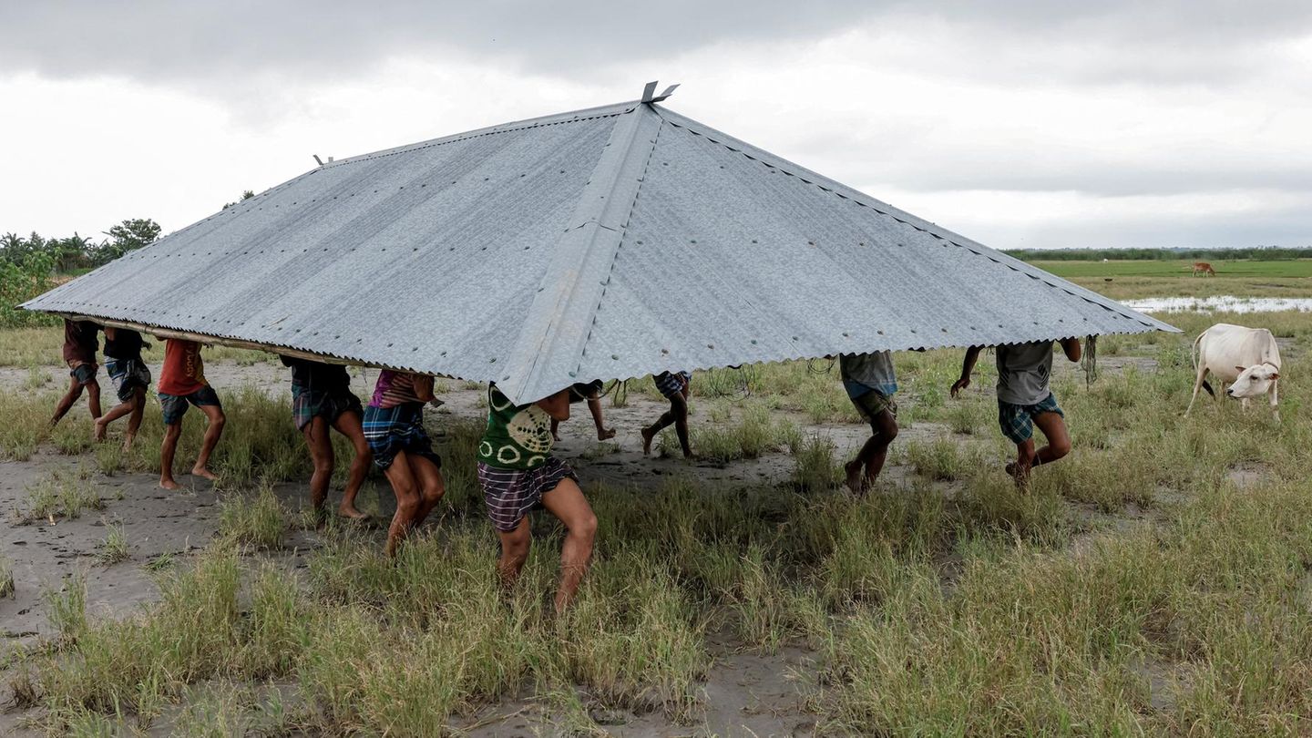 Mehrere Menschen tragen ein Dach auf ihren Köpfen