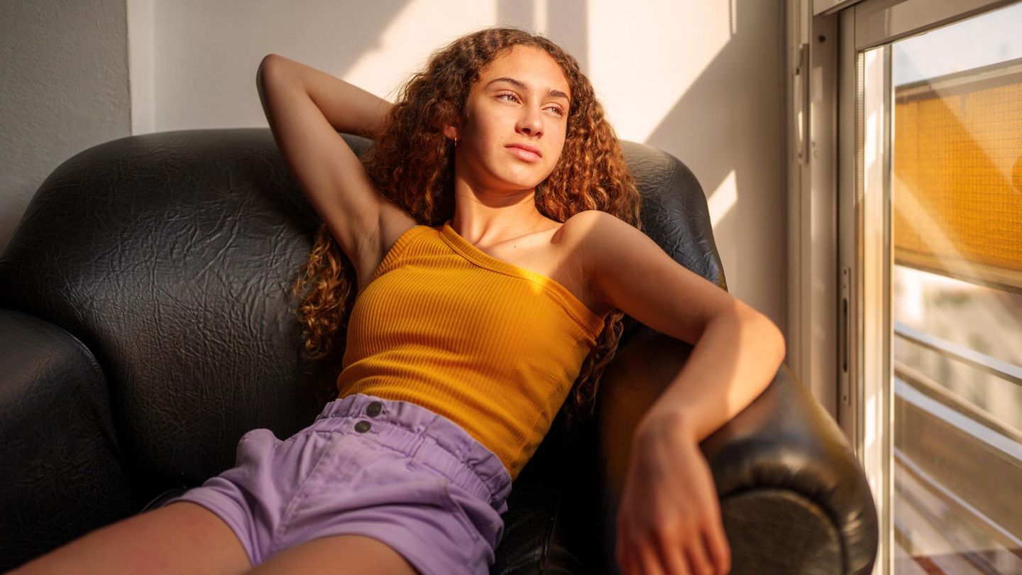 eine junge Frau sitzt gemütlich auf einem Lesersessel und schaut aus dem Fenster. Kennt sie ihre Eltern?