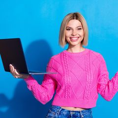 Black Friday Laptop: Eine Frau lächelt und hält dabe ihren Laptop in der Hand