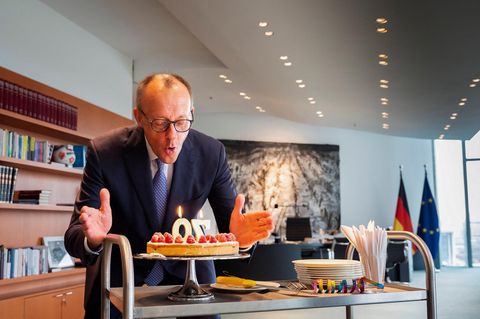 Bundeskanzler Friedrich Merz pustet Kerzen auf einer Geburtstagstorte aus