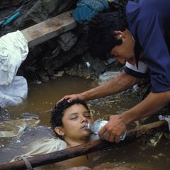 Ein Helfer gibt der völlig erschöpften Omayra Sánchez einen Schluck zu trinken