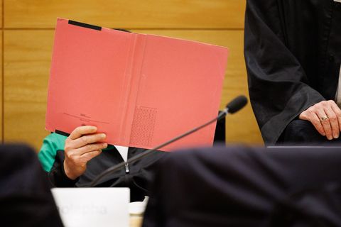 Einer der Angeklagten am Landgericht Bielefeld sitzt neben seinem Verteidiger und verdeckt sein Gesicht. Foto: Friso Gentsch/dpa