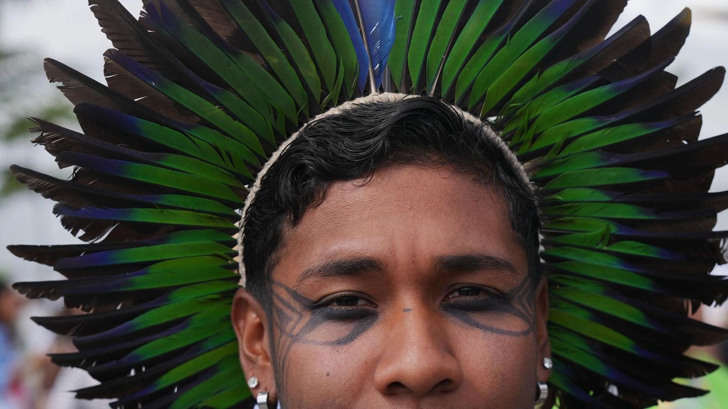 Eine Indigene mit grün-blauem Federschmuck posiert vor der UN-Klimakonferenz COP30 in Belem