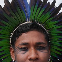 Eine Indigene mit grün-blauem Federschmuck posiert vor der UN-Klimakonferenz COP30 in Belem