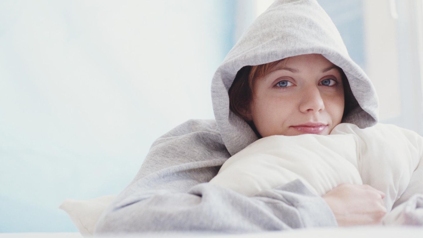 Deal: Eine Frau liegt mit kuscheligem Hoody im Bett