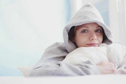 Deal: Eine Frau liegt mit kuscheligem Hoody im Bett